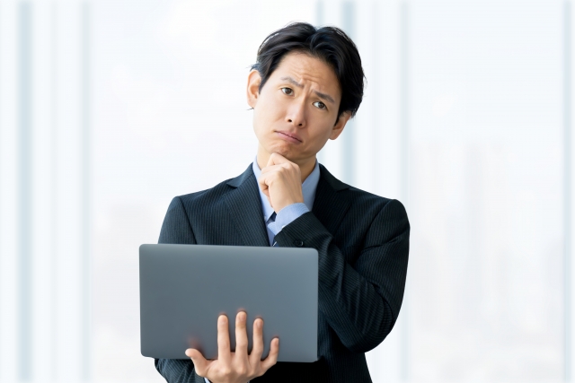 クロージングに迷って考え込む一人社長のデスクシーン