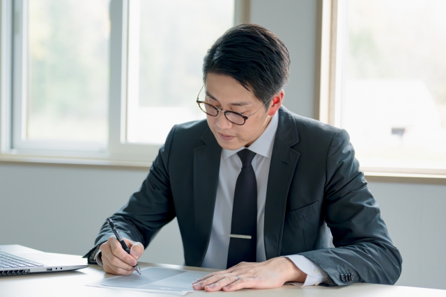 商談の準備をする男性、デスクでノートを見ながら練習している様子