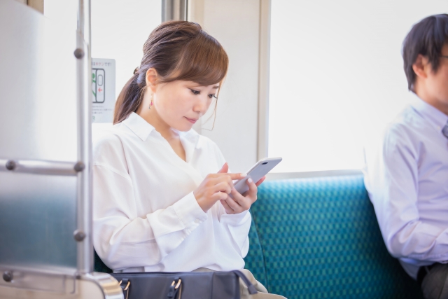 通勤電車でスマートフォンにメモを入力しているビジネスマン