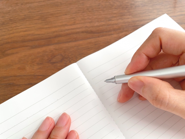 ノートに質問リストを書いている男性