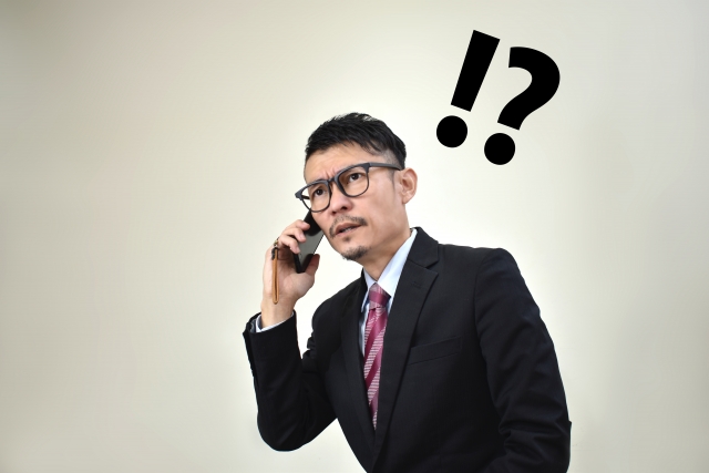 電話をかけながら困った表情のビジネスマン デスクワーク